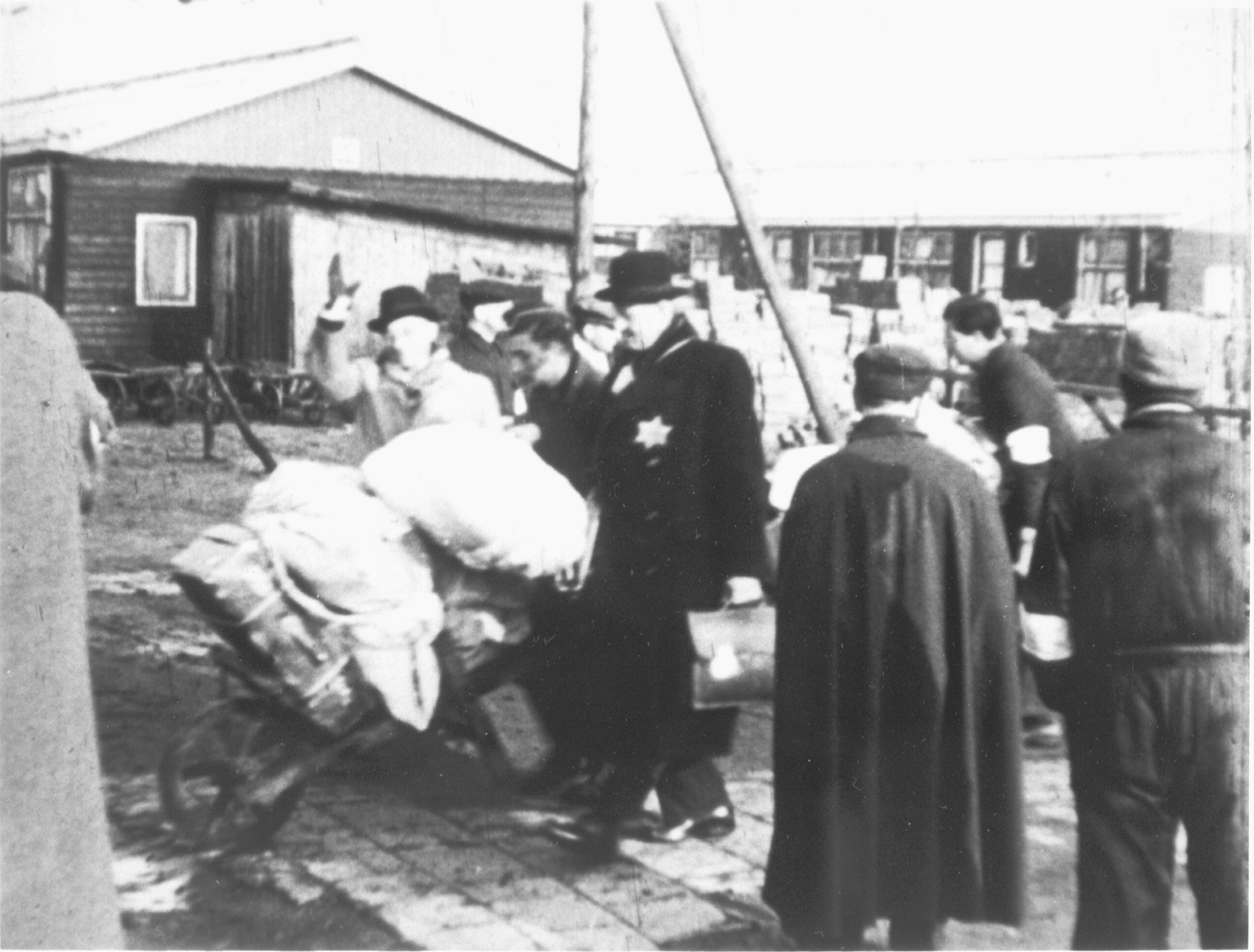 Mensen met bagage maken zich klaar voor vertrek van een transport op het perron in Kamp Westerbork. 