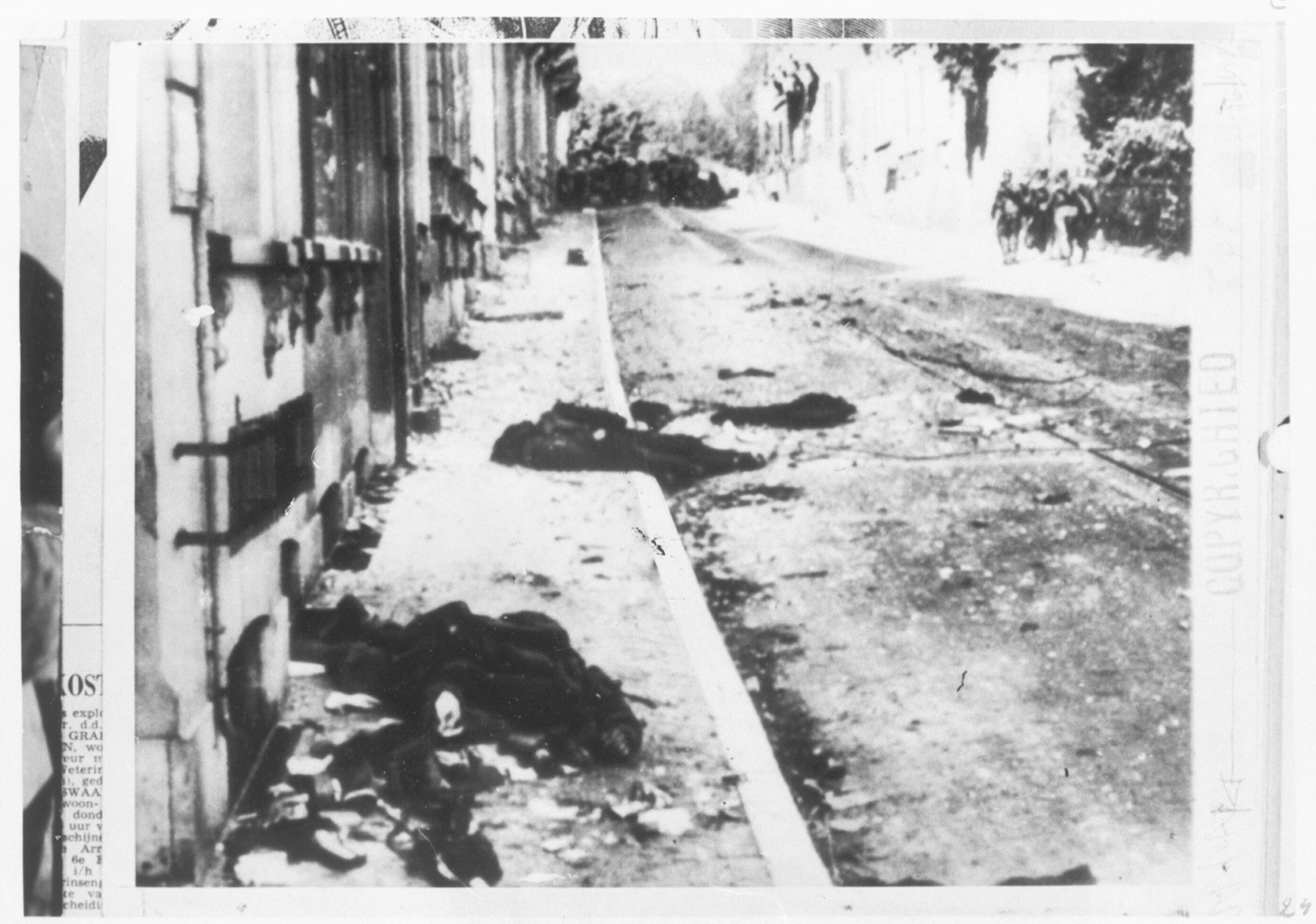 Gesneuvelde Britse militair op de Utrechtseweg in Oosterbeek, met op de achtergrond een Duitse patrouille