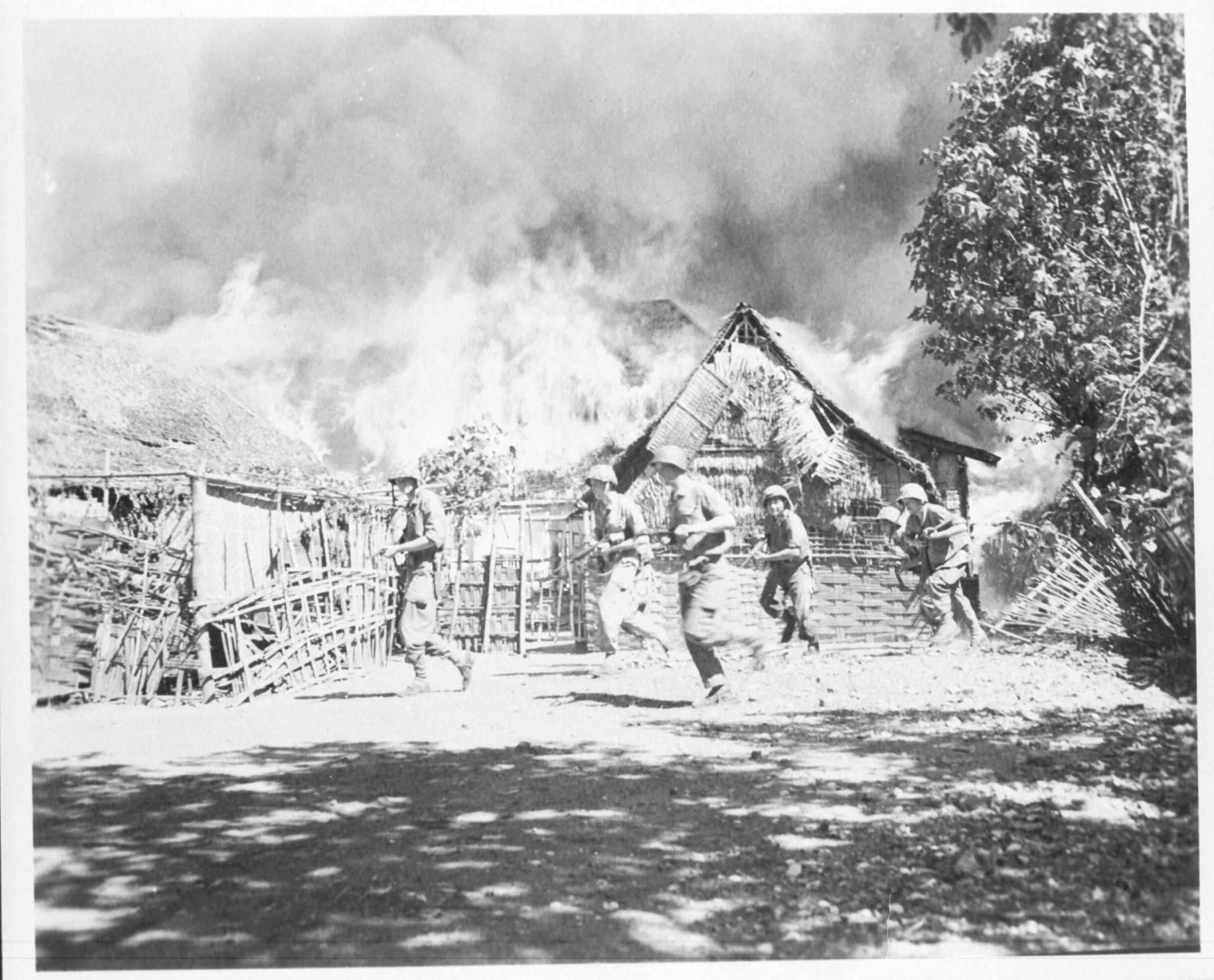 Mariniers rennen langs een brandende kampong, omgeving Surabaya, Oost-Java, 22 juni 1946. Mariniersfotograaf Hugo Wilmar/NIMH.