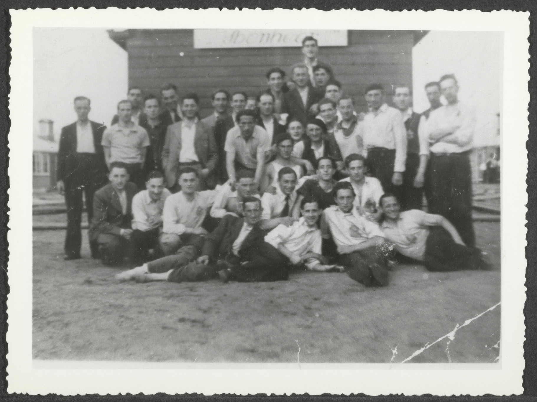 Groep mannen in joods werkkamp Ybenheer in 1942. Zittend linksonder Andries Kattenburg, naast hem met sigaret in de mond David Vos, daarnaast Jeremias Sahmentini. Direct achter Andries staand Leo Hachgenberg. Tweede rij voor, 2e en 3e van rechts vermoedelijk broers Van Crevelds. Zittend rechtsonder, aangeduid met pijl, Israel Dormits. Staand 7e van links Bernhard Fresco en uiterst rechts Adam Campignon.