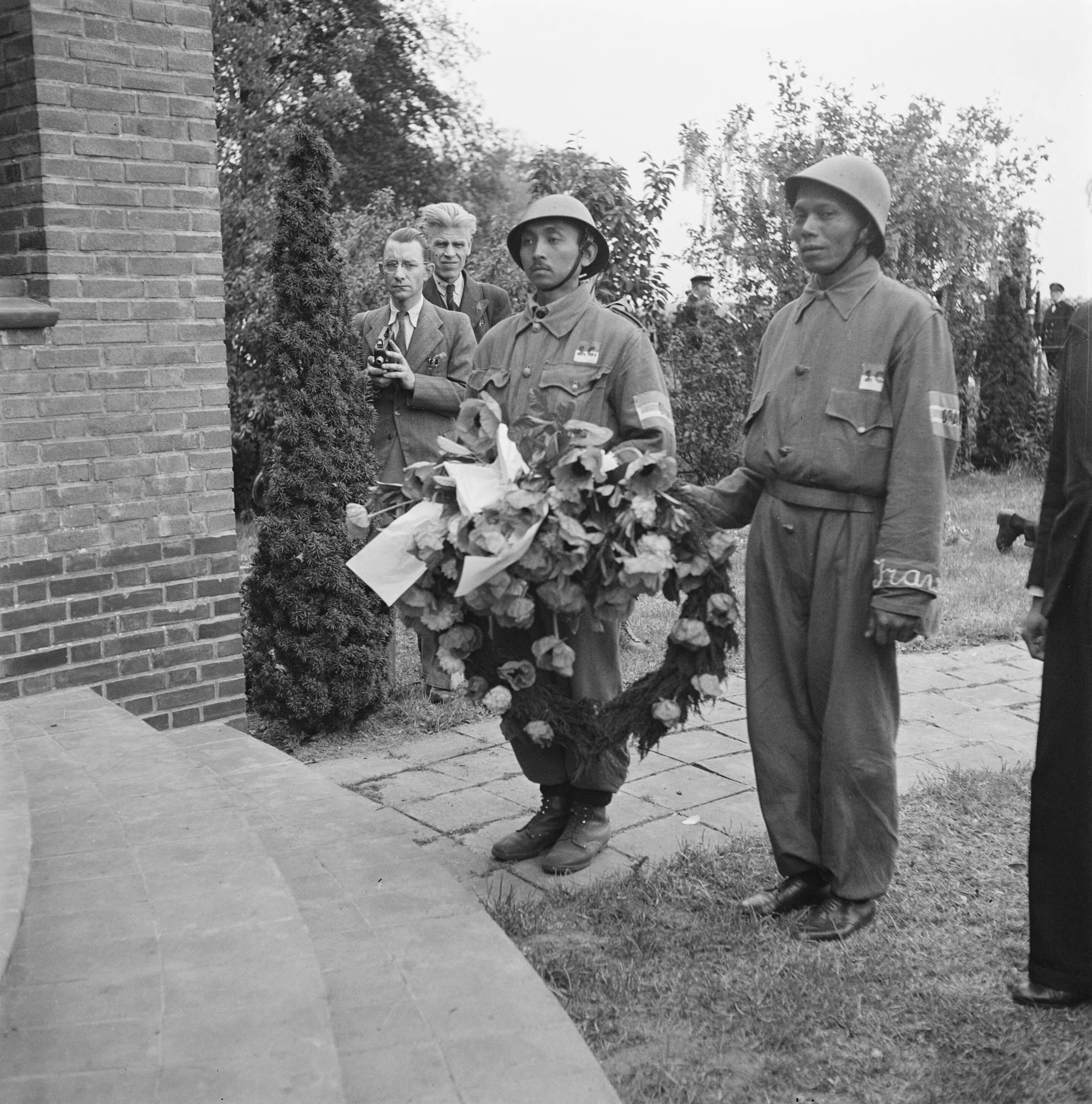 Twee Indonesische leden van de studenten van Groep Irawan van de Binnenlandse Strijdkrachten leggen een krans bij het oorlogsmonument Haagsche Schouw in Leiden op 14 mei 1945. Op de mouw van het uniform is ‘Irawan’ te lezen.