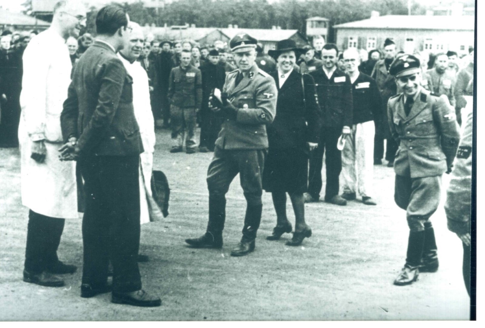 Foto van opnames van een propagandafilm in Kamp Amersfoort. Van links naar rechts: medegevangene en hulparts Jan Tückermann, kampoudste Franciscus H. M. "Frans" van de Laar, medegevangene en hulparts Bernardus Josephus Quirinus van Tilburg, Kampkommandant Karl Peter Berg, Loes van Overeem. De man rechts in uniform rechts was verantwoordelijk voor propaganda maar zijn naam is niet bekend.